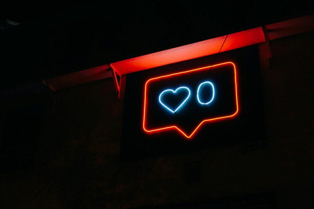 Bright neon heart icon with zero likes, symbolizing social media engagement.